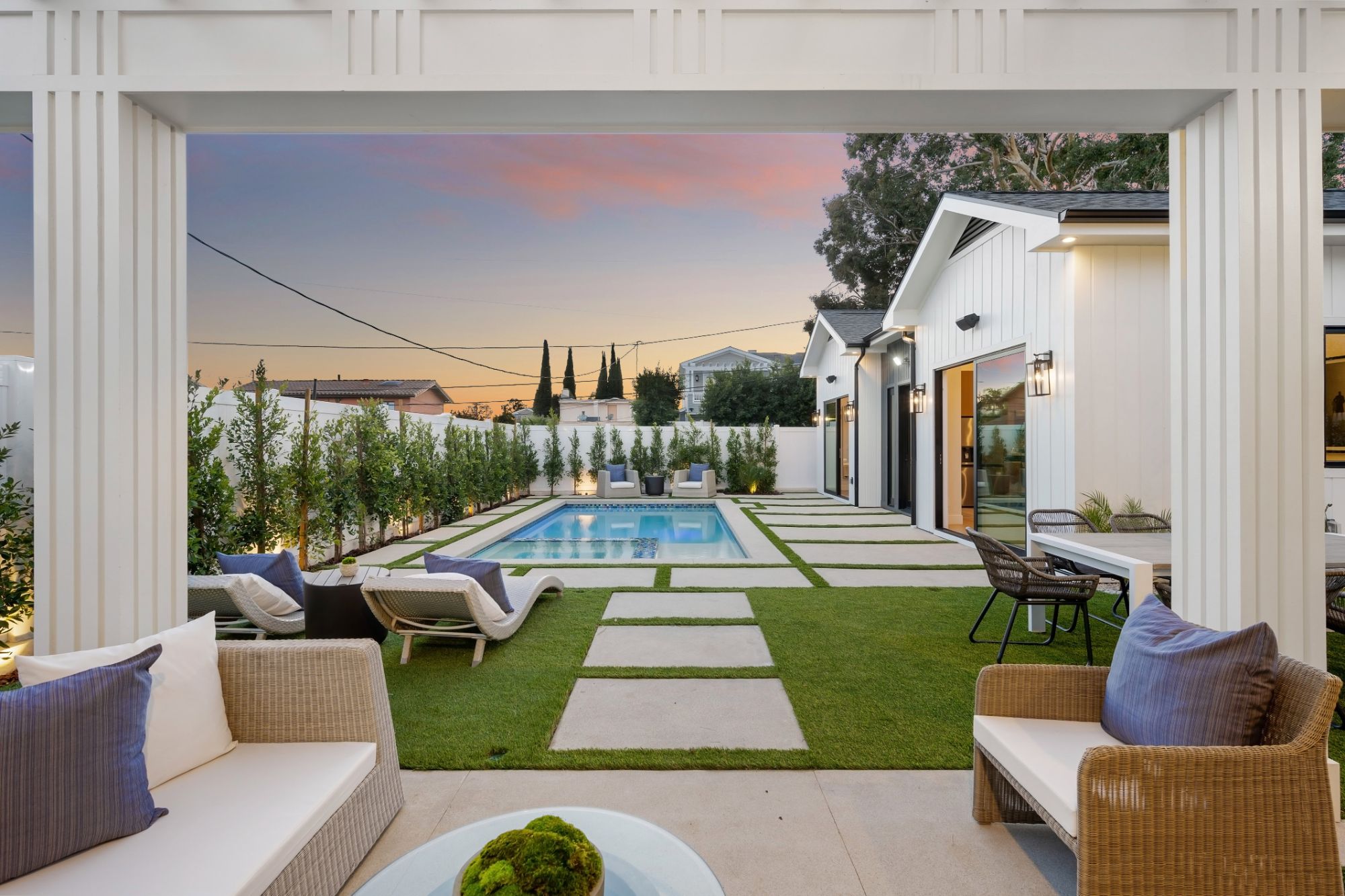 Covered patio looking out to a lawn and pool at dusk