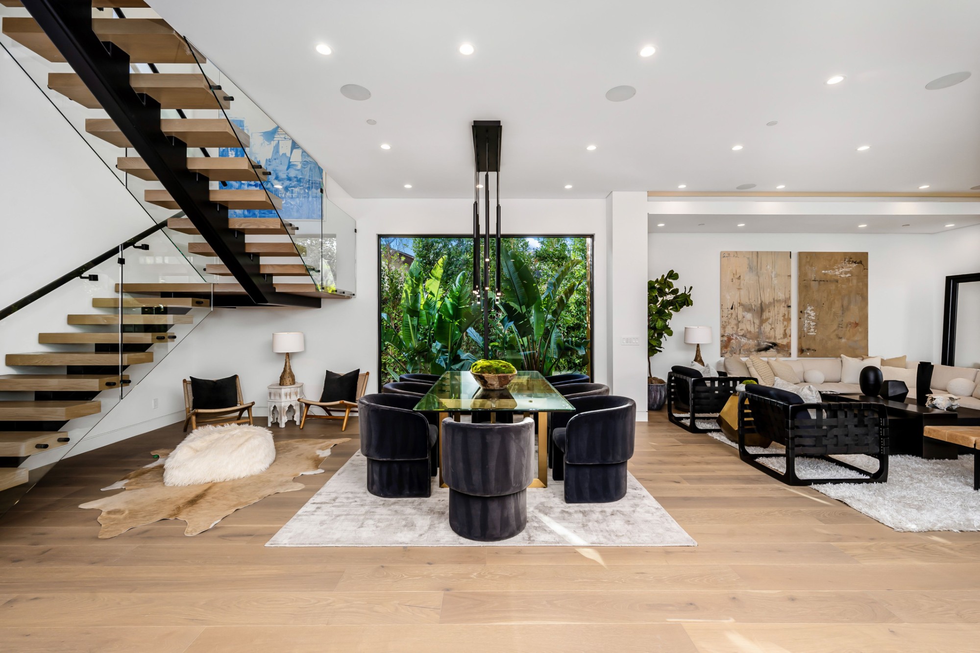 Dining room beside a floating oak staircase, with a window onto tropical planting