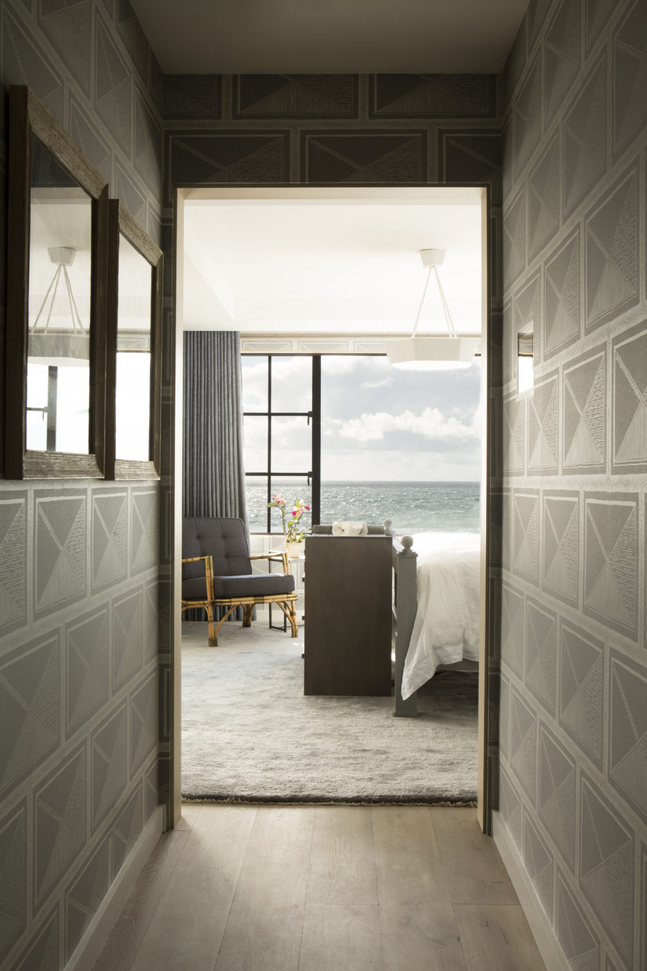 Patterned hallway opening onto a bedroom with a window overlooking the ocean