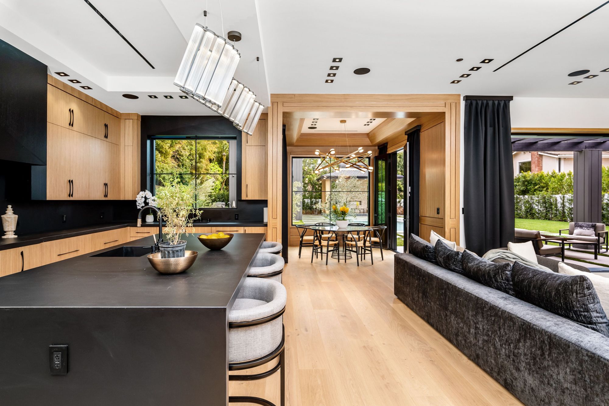 Kitchen with a black island and oak cabinetry, opening to a dining room and terrace