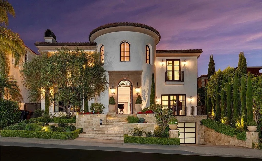 Mediterranean-style villa with a rounded entry tower, lit at dusk