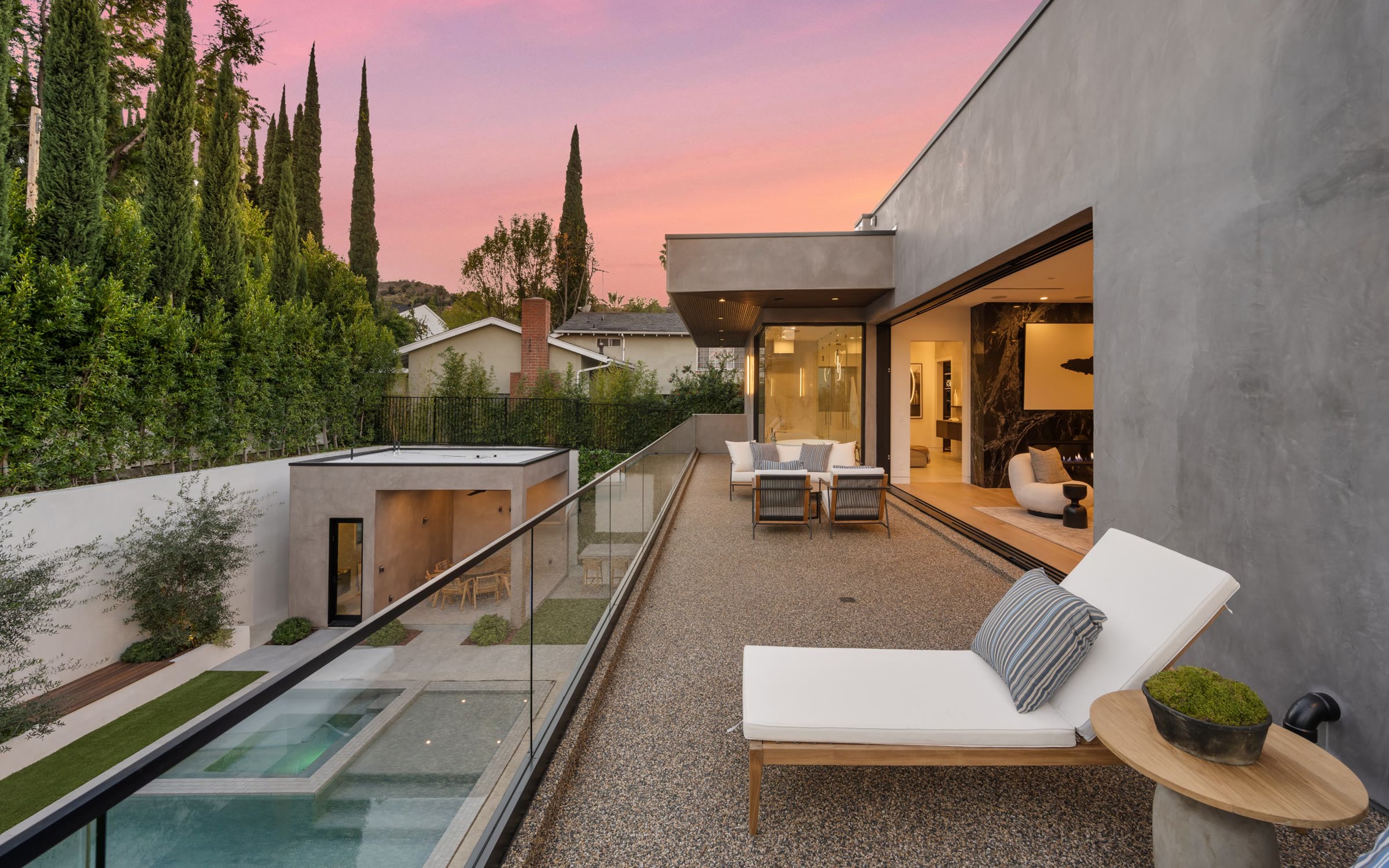 Terrace with lounge chair and pool below at sunset