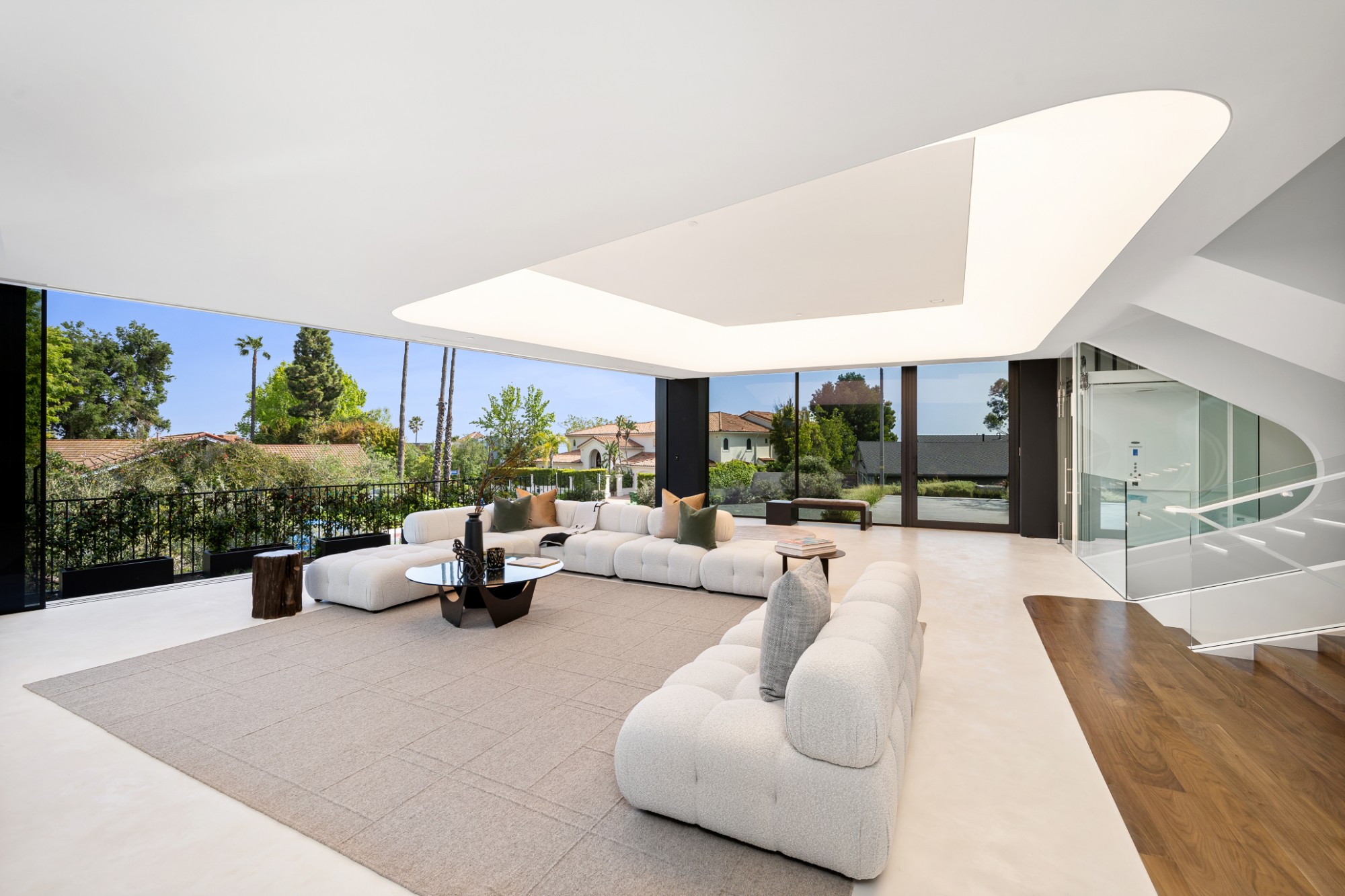 White living room with a sculpted ceiling and walls of glass to the garden